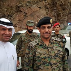 رجل أمن يحمي سيدة وطفليها في دورية من الأمطار الغزيرة بجازان